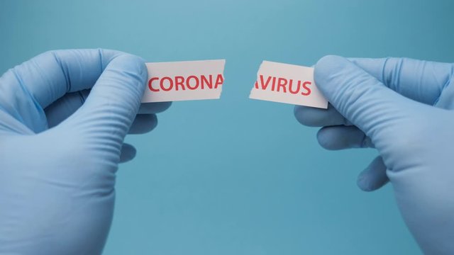 Coronavirus disease 2019. Hands in medical gloves tearing a piece of paper with coronavirus printed on it. Covid-19 Wuhan Novel Coronavirus pneumonia: COVID-19. Dangerous virus outbreak. Bioterrorism