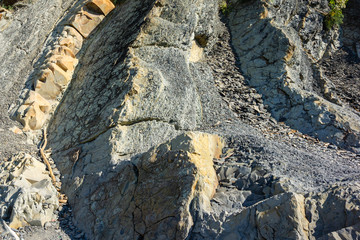 Rocky coast of Black Sea in village of Olginka, Tuapse district. Natural textures protruding on steep slopes of Caucasus Mountains. Close-up. Rock fragments and stones of different sizes as background