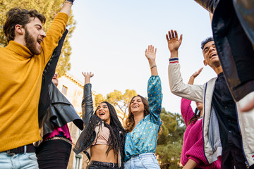 Joyful young people hands raised up. Group of multiracial people having fun together. Unity, togetherness and friendship lifestyle concept.