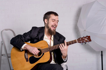 Obraz premium A man in a shirt and jacket with an acoustic guitar close-up.