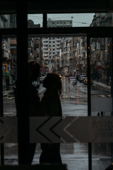 silhouette of a hugging couple against the backdrop of the city, behind a glass