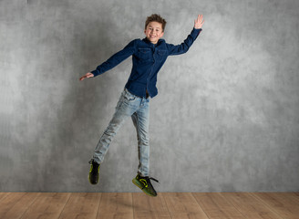 Fototapeta na wymiar heranwachsender Junge springt vor Betonwand, europäisch, allein Textfreiraum