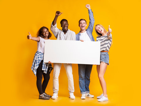 Cheerful international students with white empty board