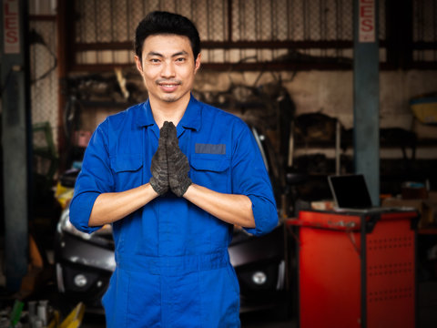 Asian man acting sawaddee mean Hello.Auto mechanic working in garage. Repair service.