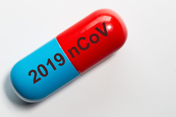 symbolic photo of a pill in blue red with the technical term for the corona virus 2019 nCoV