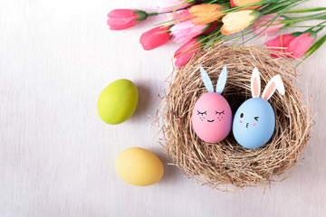 Happy easter, Easter painted eggs in nest on wooden rustic table for your decoration in holiday. Top view with copy space.