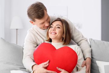 Beautiful couple with red heart at home