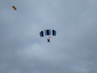 Two skydivers in the sky with colorful parachutes on a blue sky background