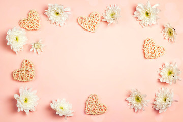 Frame of chrysanthemums and decorative hearts on a pink background.