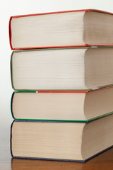 stack of piled books rest on a wooden table with copy space for your text