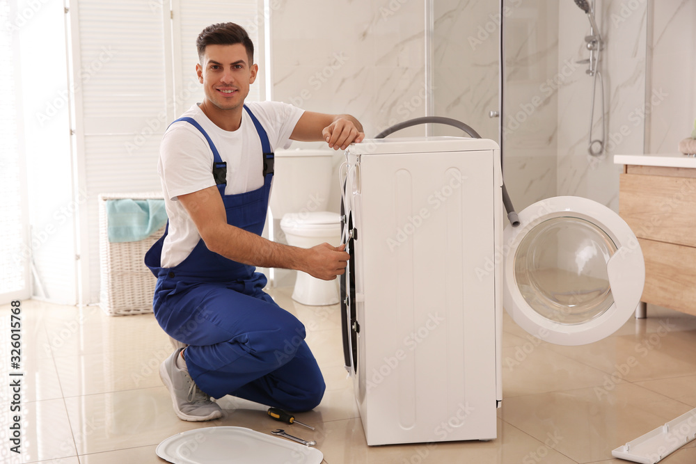 Wall mural Professional plumber repairing washing machine in bathroom