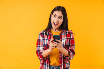Image of surprised attractive woman in plaid shirt typing on cellphone