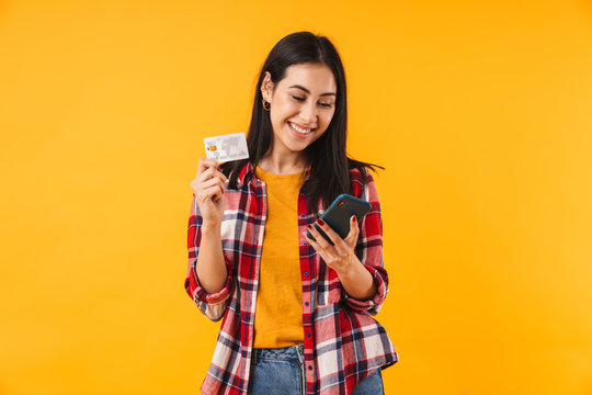 Image of happy attractive woman holding credit card and using cellphone