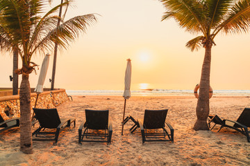 Obraz premium umbrella chair beach with palm tree and sea beach at sunrise times