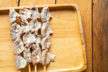 Pork intestines, cut into pieces, skewers In a wooden tray placed on a wooden table