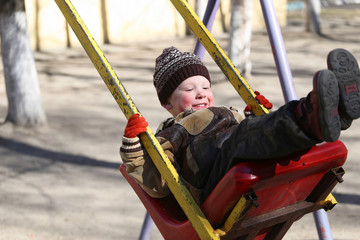 child on a swing in the playground in spring