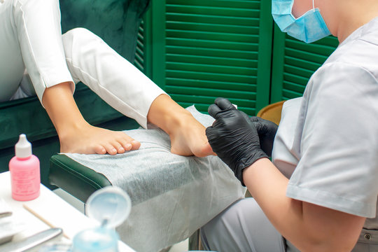 Woman receiving pedicure procedure on feet in spa salon.