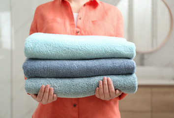 Woman holding fresh towels in bathroom, closeup