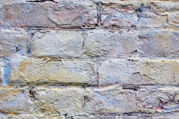 Part of an old brick wall is covered with old plaster. Shabby building facade with damaged plaster. Grunge stone wall background texture and place for text