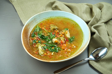 Minestrone - a classic Italian soup made from seasonal vegetables with the addition of rice or pasta in a blue bowl on a wooden background