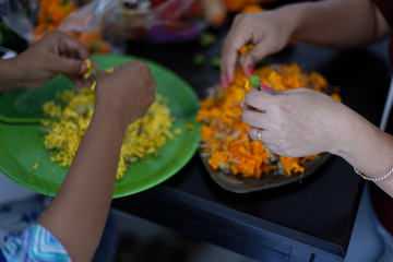 Two Indian brunette women are arranging together the orange and yellow flowers for the celebration of Diwali/Durga puja. Indian lifestyle and Diwali celebration.