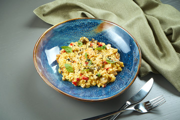 The classic dish of Italian cuisine - risotto with seafood, vegetables and spices in a blue bowl on a wooden background
