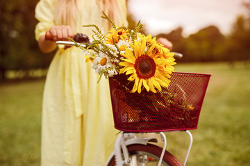 Crop woman pushing bicycle with flowers