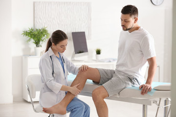 Obraz premium Female orthopedist examining patient's leg in clinic