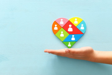image of heart shape tangram puzzle blocks with people icons over wooden table ,human resources and...