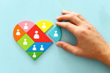image of heart shape tangram puzzle blocks with people icons over wooden table ,human resources and...