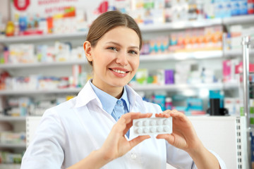 Professional pharmacist with pills in modern drugstore