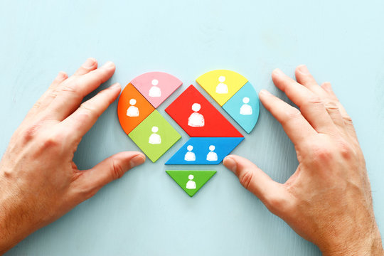 image of heart shape tangram puzzle blocks with people icons over wooden table ,human resources and management concept