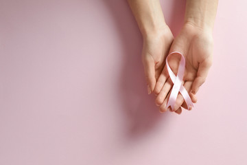 Woman holding pink ribbon on color background, top view with space for text. Breast cancer awareness