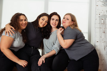 Young caucasian women in casual clothes having fun together. Friends sitting near by window and...