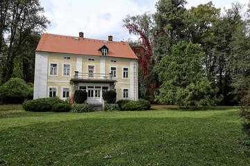 Fototapeta na wymiar Yellow and white villa with red roof in large garden