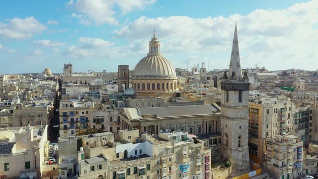 Aerial view of Valletta - capital of Malta country. Daylight, blue sky with clouds. Mediterranean sea. Camera moves from down to forward and up 