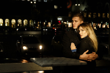 couple in love embracing against a dark background, night, rain, buildings in the city, a park, smiling, attraction. the guy hug the girl. Valentine's Day