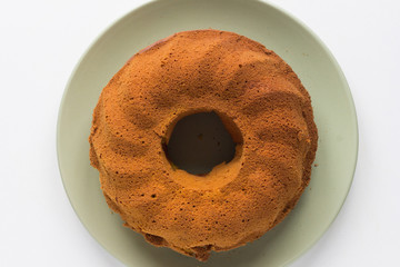 Top view of baked pumpkin cake on green plate on the white background