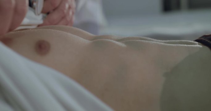 Close view of listening to the sick male chest with phonendoscope in hospital