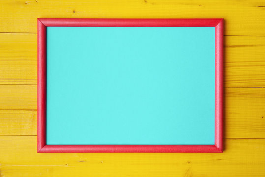 Blue paper card in red frame on yellow wooden planks