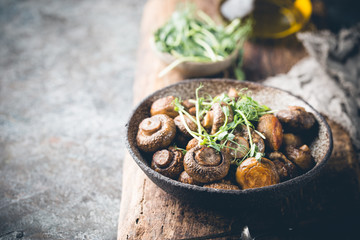 Baked champignons mushrooms with butter and roasted garlic in a bowl. Healthy food concept.