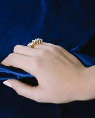 Close up of elegant diamond ring on the finger with blue background, stock image