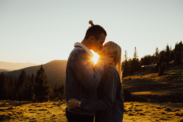 Profiles of romantic couple kissing on background of sunset. Close-up of a young couple kissing each other in the light of sunset.