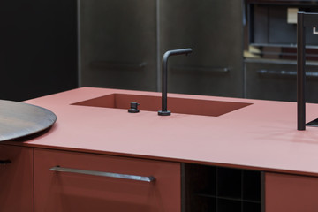 Trendy kitchen of dark red color, one-piece countertop and sink, modern designer kitchen with an island