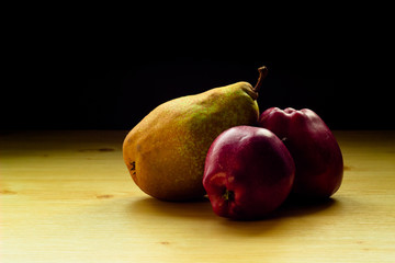 Red apples and a pear on the wooden table with checkered tablecloth
