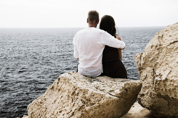 Fototapeta na wymiar Love couple looking at the sea on rocky beach stock image