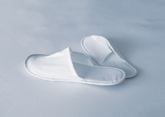New eco-friendly fabric disposable slippers in a transparent package lie on white bedsheet