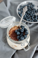 Delicious dessert: tiramisu in a glass jar and natural yogurt in a glass cup with fresh berries, strawberries and blueberries. 