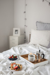 Beautiful breakfast in bed: Viennese Belgian waffles decorated with berries, a plate with strawberries and blueberries