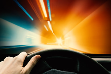 Obraz premium Hand on Steering Wheel - Driving Car in Tunnel. High Speed Concept, Blurred Motion Design.